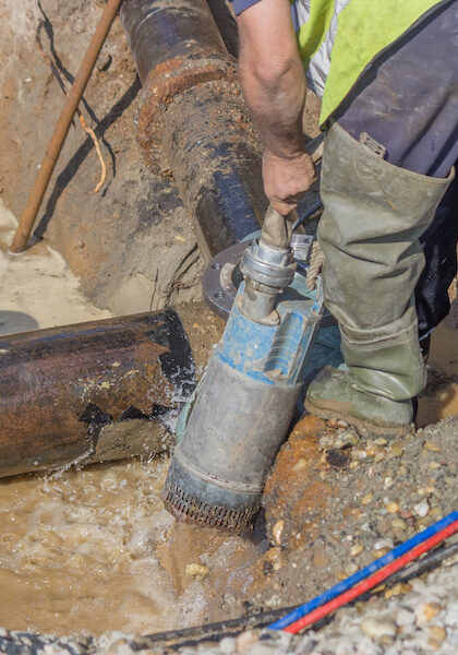 Submersible water pump drain trench. Water pumping on building area. Selective focus.
